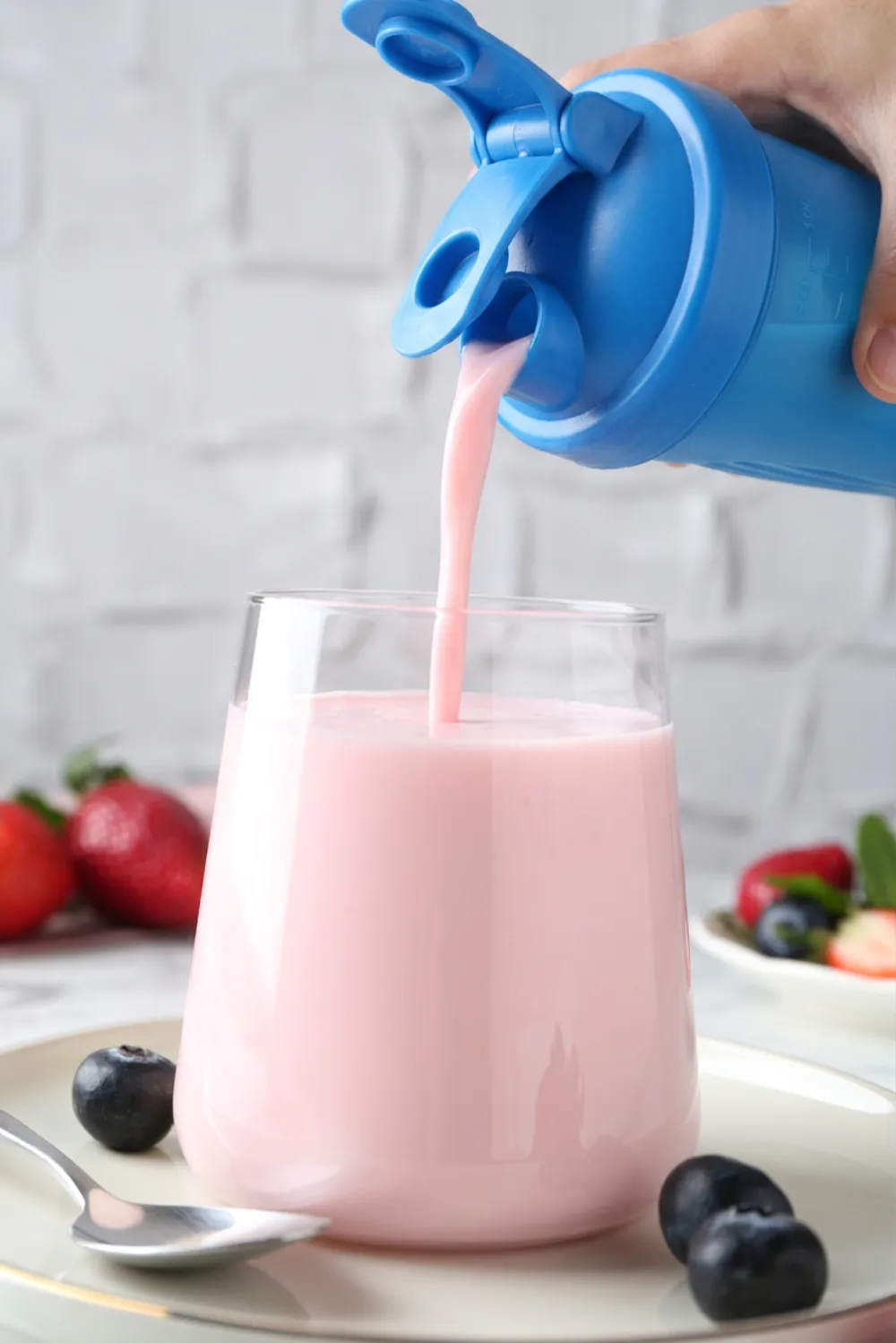 Strawberry shake being poured from a shaker into a glass